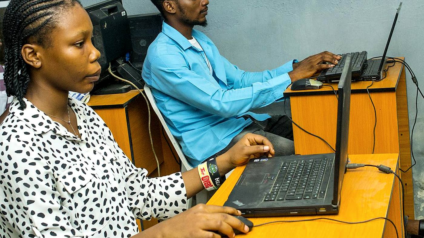 Student learning web development on a laptop with a GeoTech Academy instructor